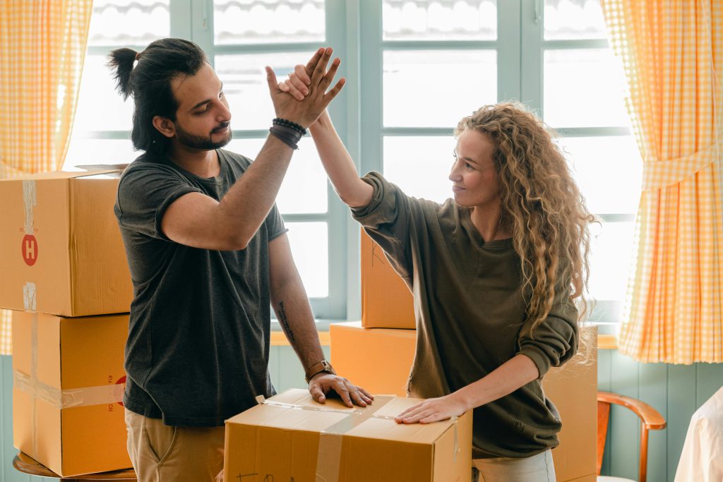 Couple high-fiving over moving boxes - visit rsd-storage.com. 